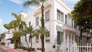 Villa Pardo Glengarry House, a white building with pink trim, palm trees, and a white fence. - Pantera Rosa (Miami Beach)