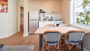 A compact kitchen with a refrigerator, stove, and dining area with two chairs. - Pantera Rosa (Miami Beach)
