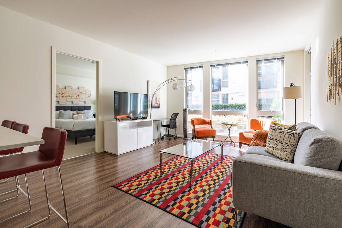 A modern living room with a sofa, armchairs, a dining table, and a TV.