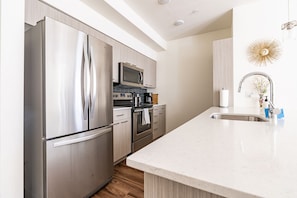 A modern kitchen with stainless steel appliances, a microwave, and a sink.