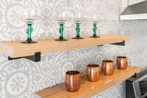 A kitchen with a patterned backsplash, a wooden shelf with glass and copper mugs, and a toaster oven. - ✨Amazing Views✨Backyard Trails 🏜️Close to National Park, Shops, Restaurants ☕️ (Joshua Tree)