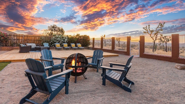 A patio with four Adirondack chairs, a fire pit, and a wooden deck. - ✨Amazing Views✨Backyard Trails 🏜️Close to National Park, Shops, Restaurants ☕️ (Joshua Tree)