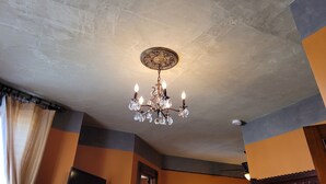 Une pièce avec un plafond à motifs, un lustre et des murs peints dans deux couleurs différentes.