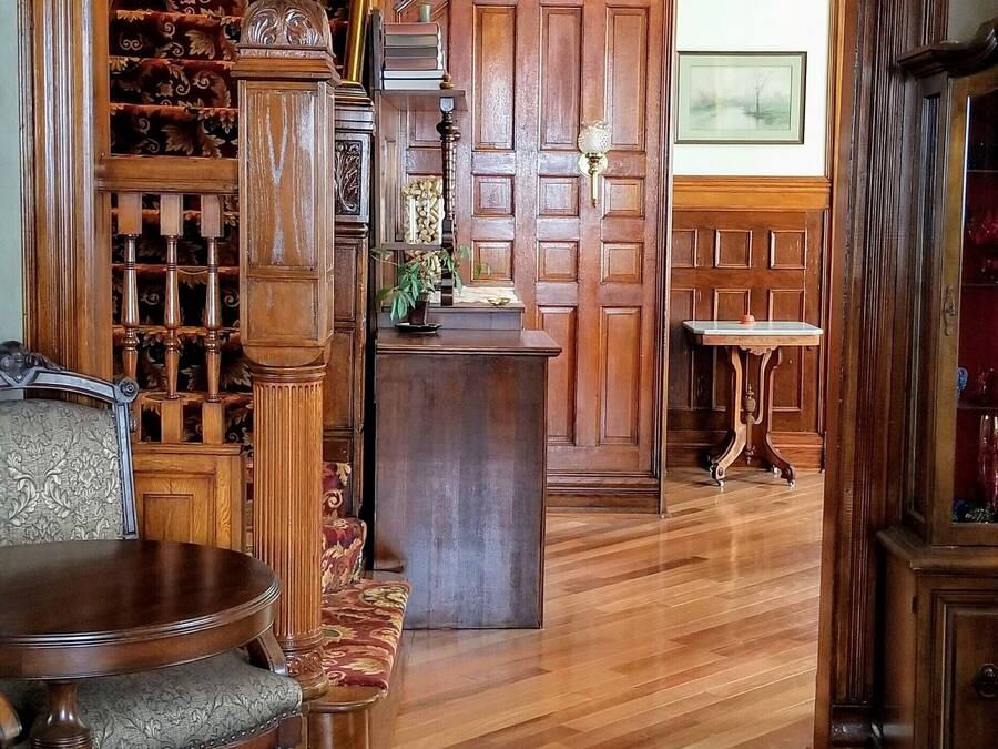 A grand hallway with a wooden staircase, a chandelier, and a patterned floor.