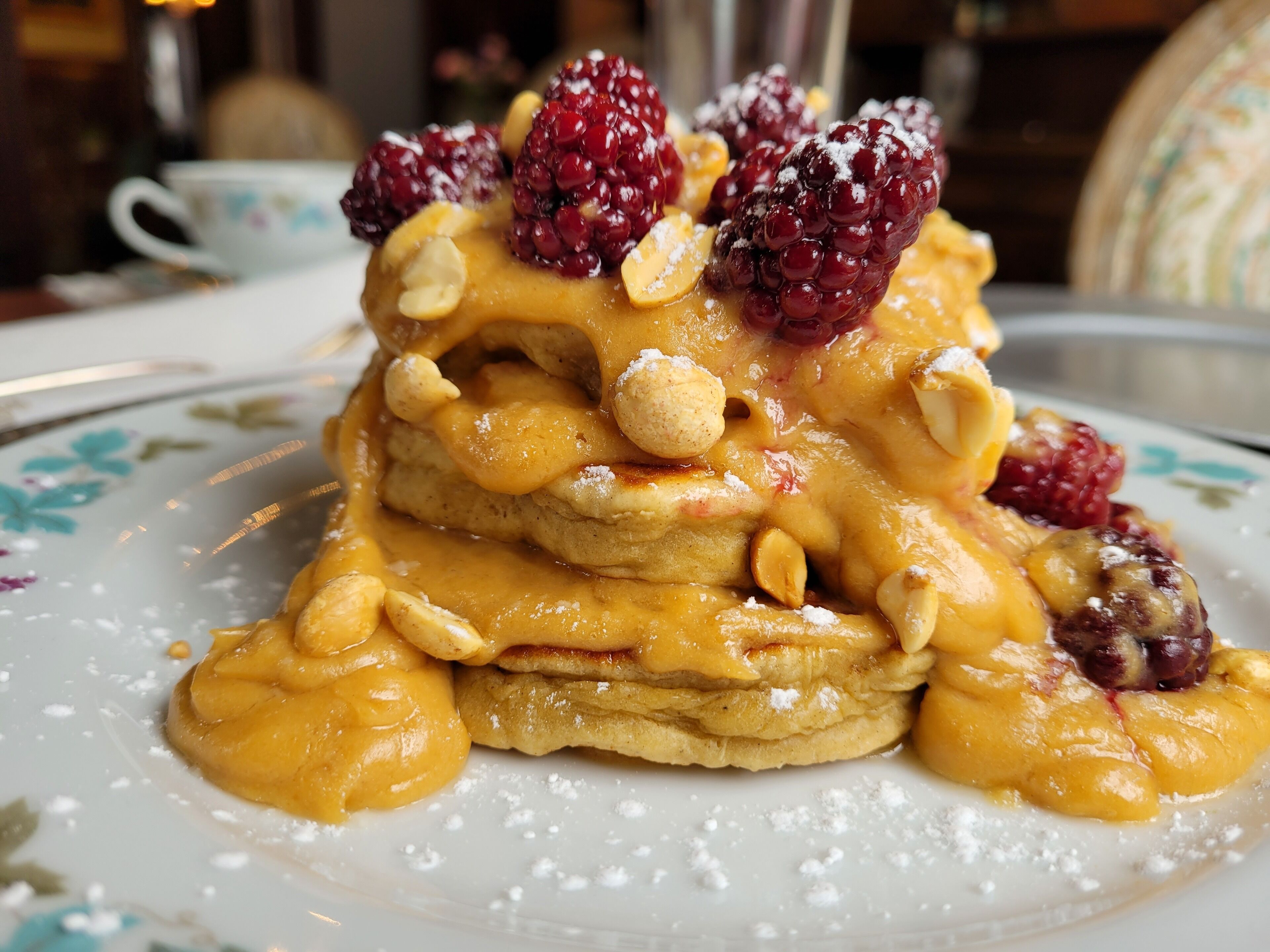 Una pila de tortitas con fruta y nueces sobre un plato.