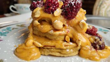 Una pila de tortitas con fruta y nueces sobre un plato.