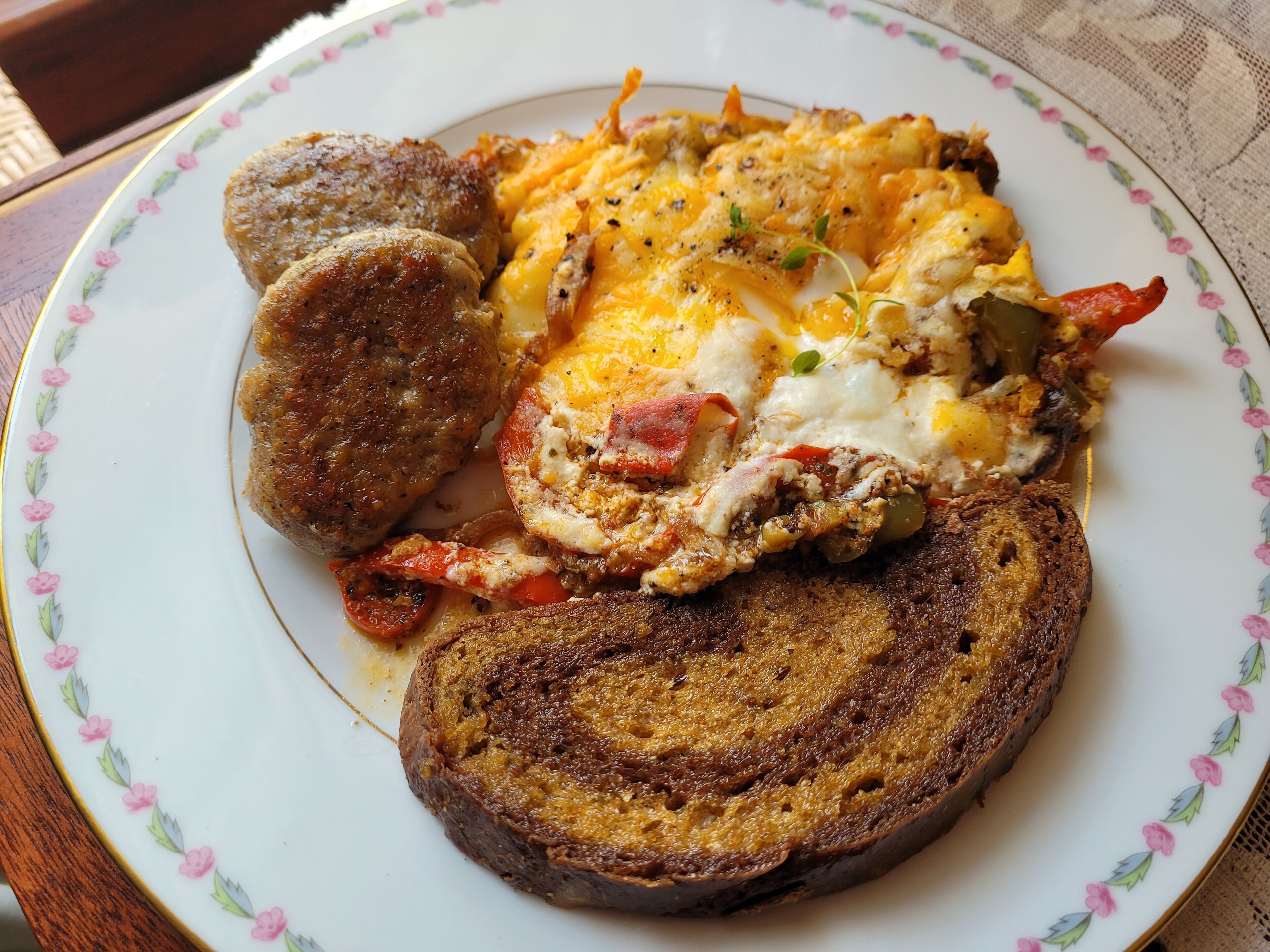 A plate with scrambled eggs, sausage, toast, and a side of vegetables.