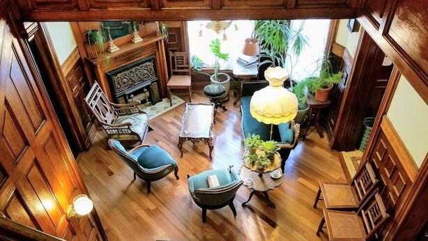 Une pièce spacieuse avec un plancher en bois, une cheminée, une table à manger et plusieurs chaises.