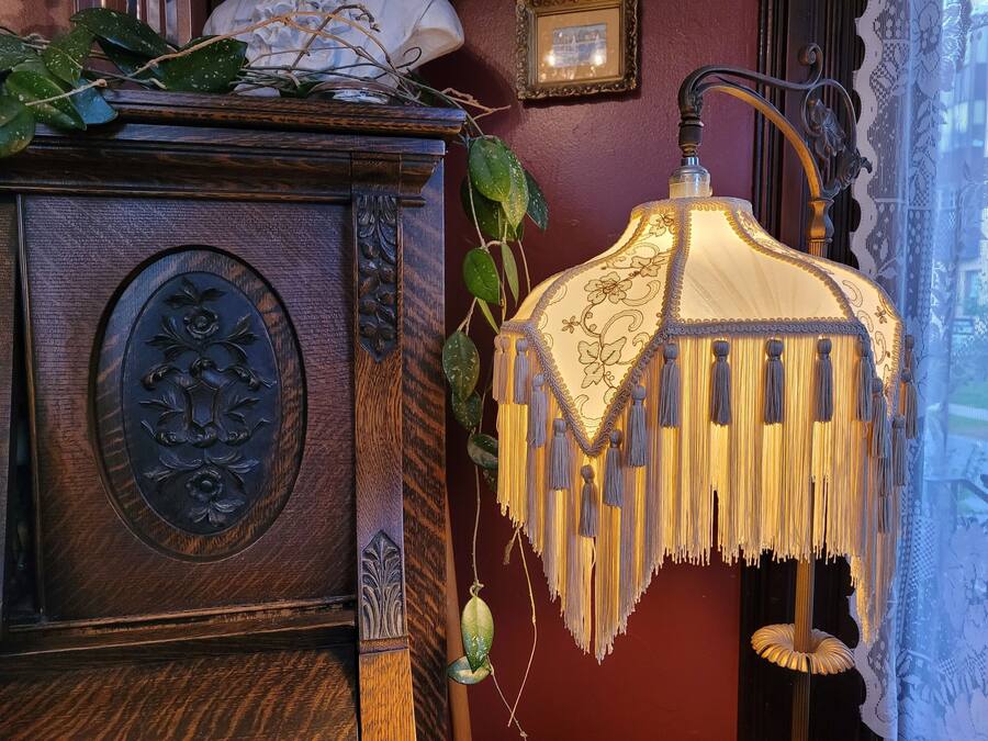 A wooden cabinet with a decorative floral panel and a hanging lamp with tassels.