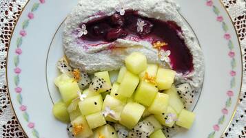 A plate of food with a creamy dessert, fruit cubes, and a decorative plate.