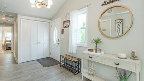 A hallway with a white door, a mirror, a console table, and a small plant. - Private Waterfront Home Nestled In A Quiet Section Of Lake Hopatcong (Jefferson)