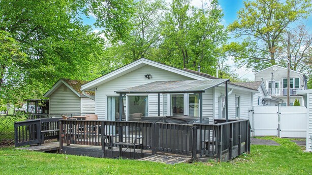 Einbungalow mit einer überdachten Veranda und einem umzäunten Deck.