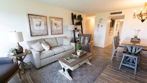 A living room with a sofa, coffee table, and dining area with chairs. - Mountaintop condo with indoor and outdoor pools (Gatlinburg)