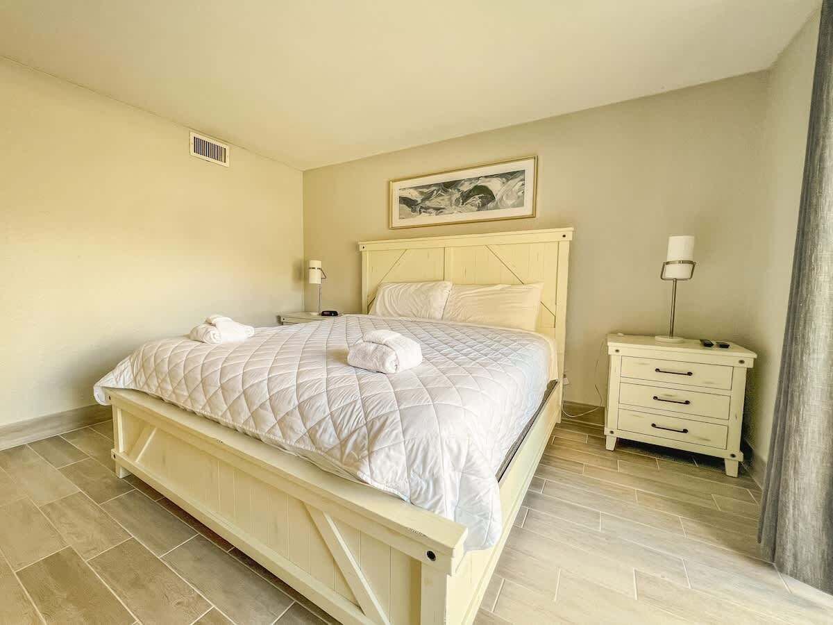 A bedroom with a bed, bedside tables, a nightstand, and a painting on the wall.