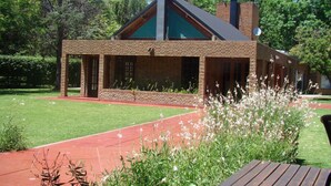 A brick building with a sloped roof, large windows, and a covered patio area. - Parador 15 (Funes)