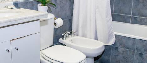 Un baño con inodoro, bidé, lavamanos y espejo.