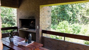 An outdoor patio with a brick wall, wooden table, and a brick oven. - Parador 15 (Funes)