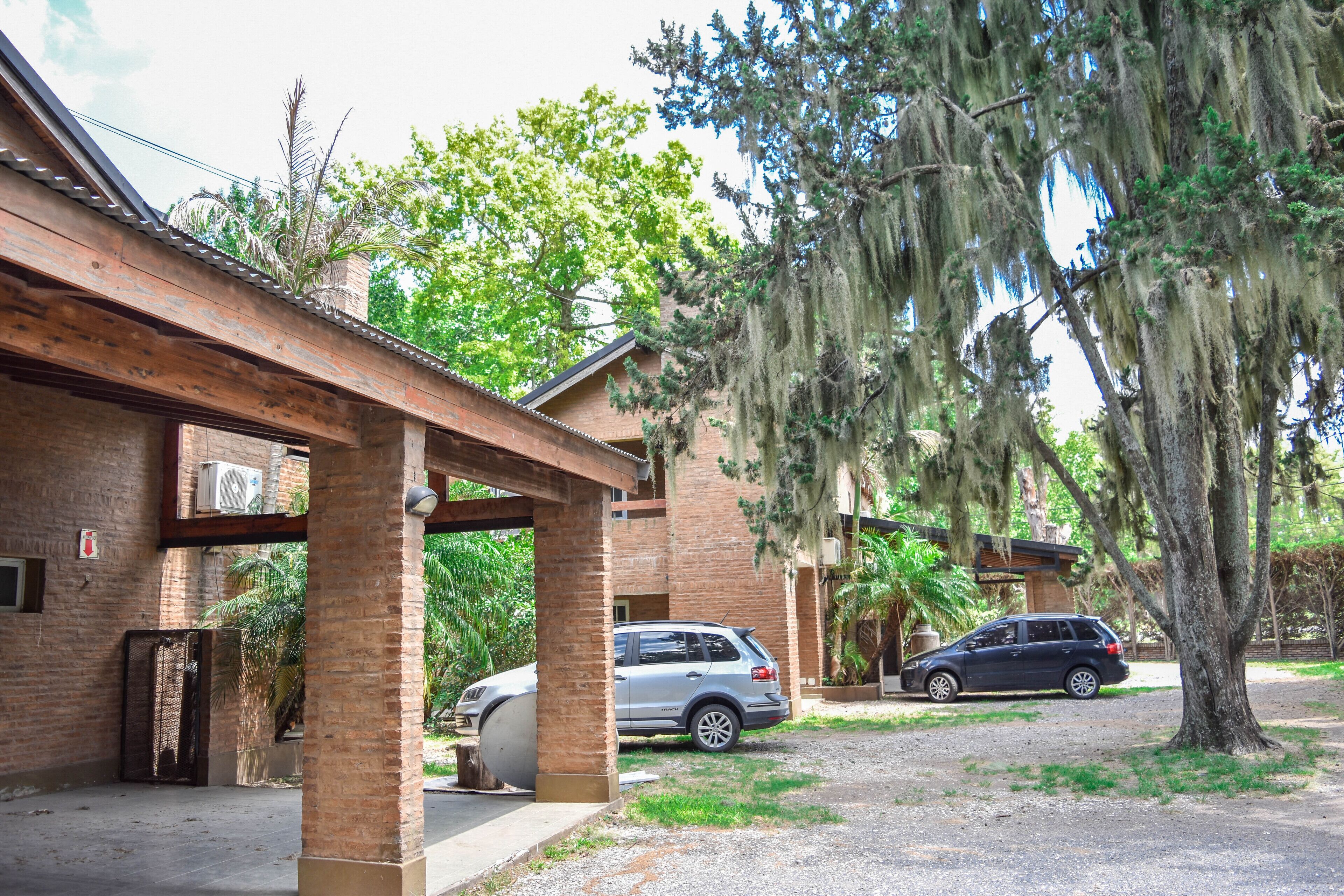 A building with a brick exterior, a covered patio area, and a car parked in front.