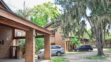 A building with a brick exterior, a covered patio area, and a car parked in front.
