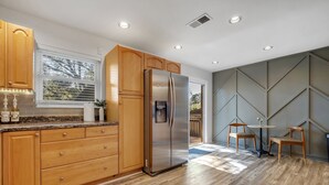 Une cuisine moderne avec des meubles en bois, un réfrigérateur en acier inoxydable et un coin repas comprenant deux chaises et une petite table.