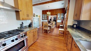A kitchen with wooden cabinets, a gas stove, and a dining area with a chandelier.
