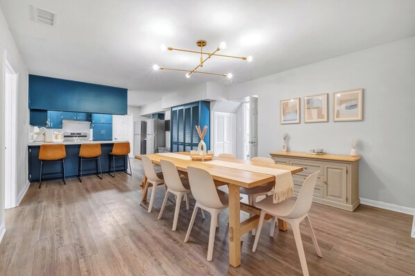 A modern kitchen with blue cabinets, a wooden dining table, and a pendant light. - MAGNOLIA BARN \\ 7-8 Bedrooms \\ 8+ Parking Spots \\ 2 Miles from FSU\Capitol (Tallahassee)