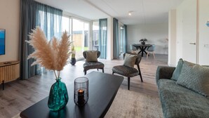 Ein modernes Wohnzimmer mit einer Couch, einem Couchtisch und einem Essbereich im Hintergrund.