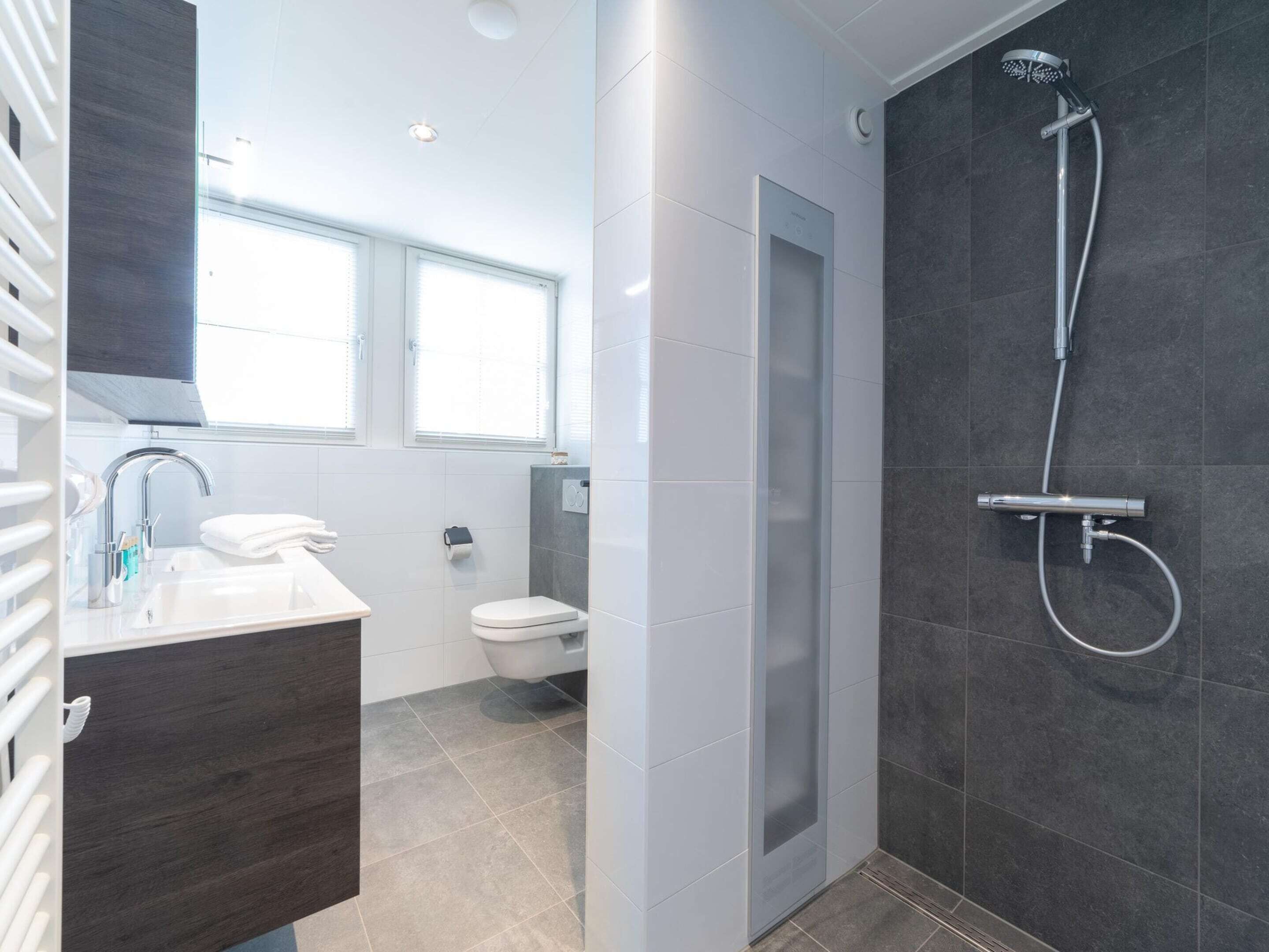 A modern bathroom with a shower, toilet, and sink.