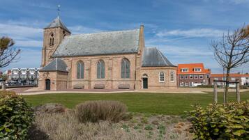 A historic church with a prominent tower and arched windows, surrounded by a well-maintained lawn and a brick wall.