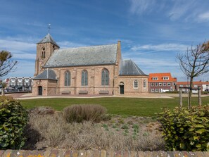 A historic church with a prominent tower and arched windows, surrounded by a well-maintained lawn and a brick wall.