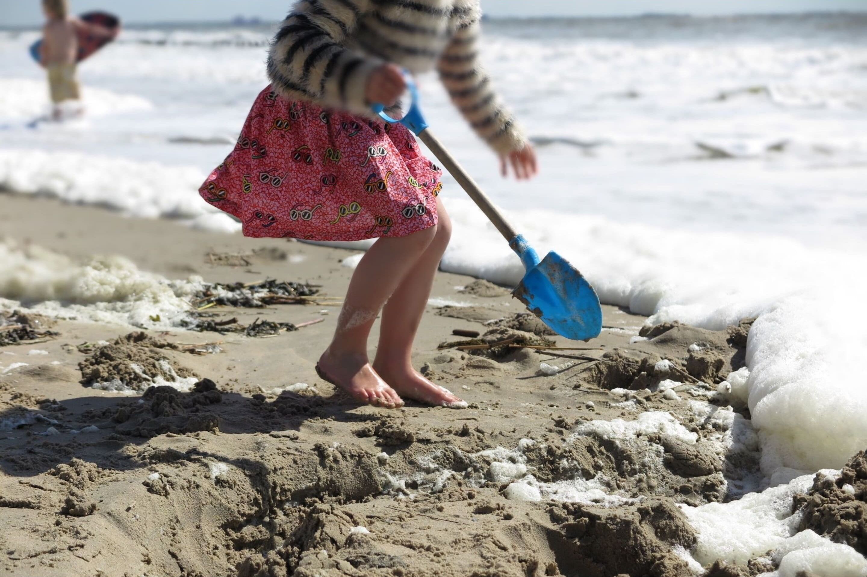 A sandy beach with a child playing.