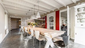 A spacious dining area with a long wooden table, white chairs, and pendant lighting. - Spacious Holiday Home De Pauwenhof (Heiloo)