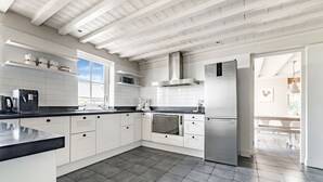 A modern kitchen with white cabinetry, a stainless steel refrigerator, and a large window providing natural light. - Spacious Holiday Home De Pauwenhof (Heiloo)