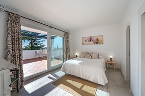 Relax in this serene bedroom with a large bed, sliding glass door to a patio, and a beautiful view.