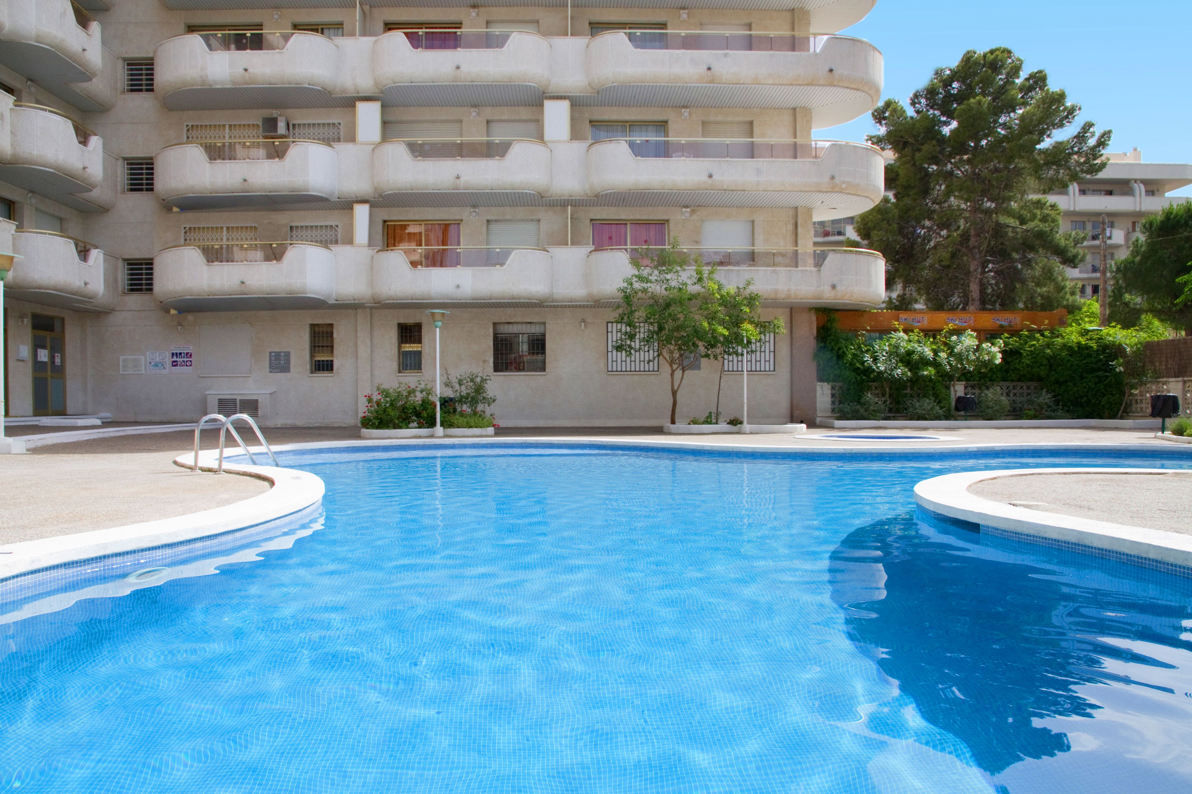 A swimming pool area with a multi-story building in the background.