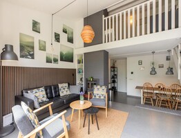 Una sala de estar moderna con un sofá, sillas, chimenea y un comedor con mesa y sillas.