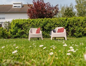 Two outdoor chairs with cushions in a grassy area with a hedge and a building in the background. - Comfort Holiday Home Near Beach (Nieuwvliet)
