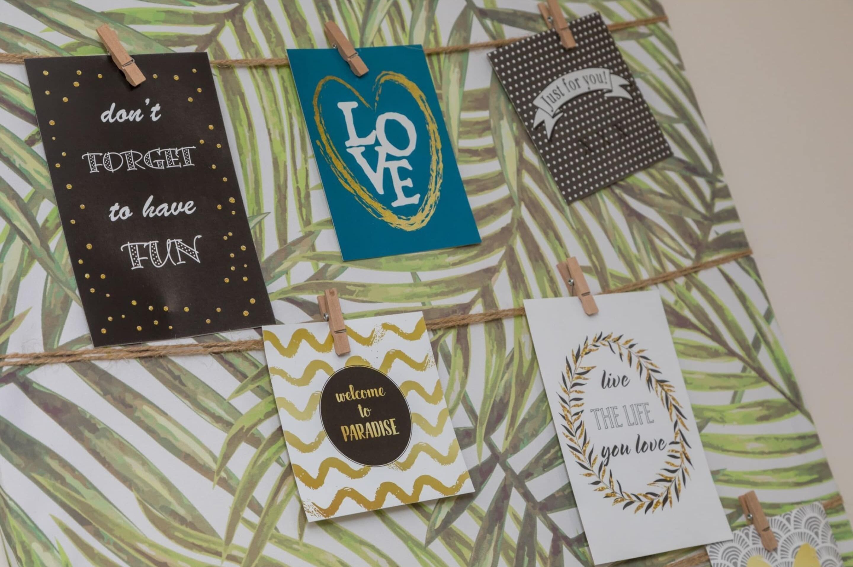 Four cards with motivational phrases, each clipped to a string against a patterned background.