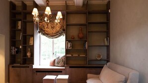A cozy living room with a sofa, a wooden bookshelf, and a decorative chandelier. - Stately 16-person Manor Farm in South Limburg (Schimmert)