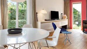 Uma sala de estar moderna com uma mesa de jantar redonda, uma televisão e uma lareira.