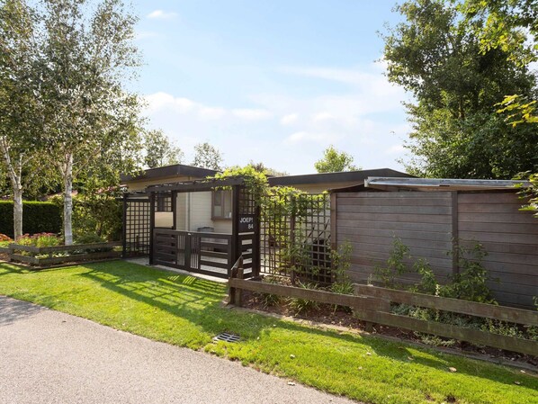 A gated residential area with a wooden fence, a small house with a porch, and a well-maintained lawn.