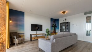 A modern living room with a sofa, a TV, a wooden bench, and a bookshelf. - Apartment on Tholen by Oosterschelde Estuary (Scherpenisse)