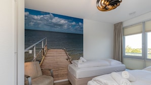 A hotel room with a bed, a chair, a wooden deck, and a view of the sea. - Apartment on Tholen by Oosterschelde Estuary (Scherpenisse)