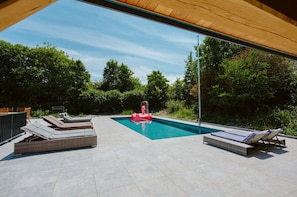 Uma piscina com espreguiçadeiras e um boi inflável vermelho.