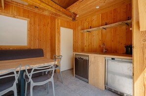 Interior de uma cabana de madeira com área de jantar, pia e máquina de lavar louça.