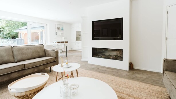 A modern living room with a sofa, a round coffee table, and a fireplace. - Luxurious 16-person Villa With Swimming Pool Sauna Outdoor Kitchen With BBQ (Ouddorp)