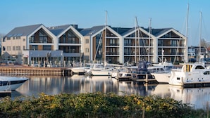 Un port de plaisance doté de bâtiments modernes, de bateaux amarrés et d’une étendue d’eau calme.
