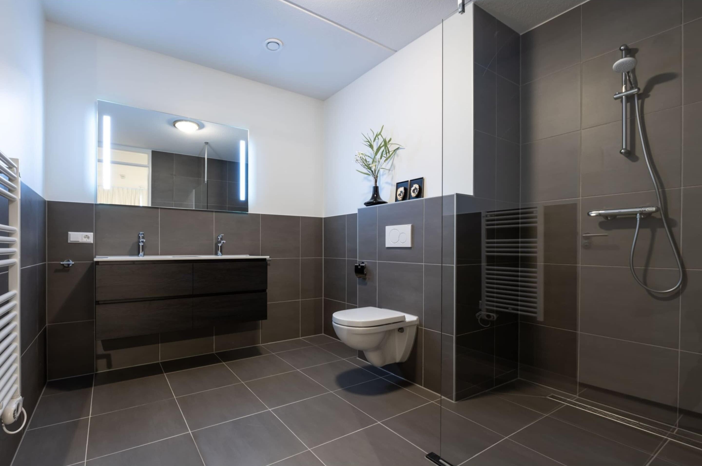 Een moderne badkamer met douche, toilet en wastafel.