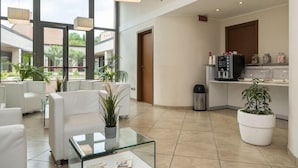 Un vestíbulo de hotel moderno con una zona de estar, una mesa de centro de vidrio y una kitchenette.