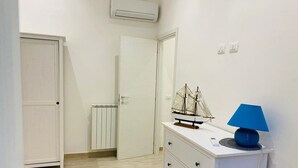 A room with a white dresser, a ship model, and a blue lamp. - Villa in Sicily With Sea Access (Santa Flavia)